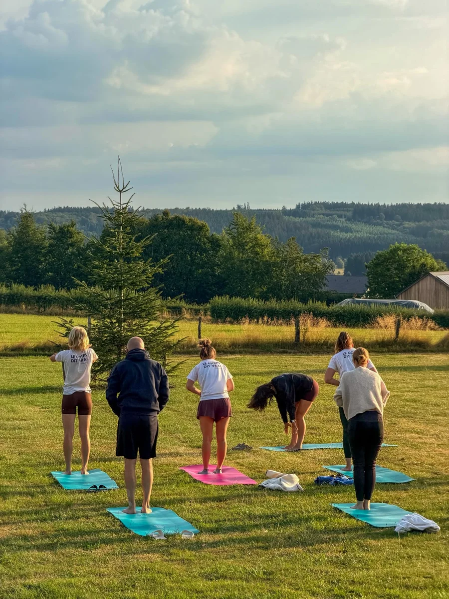 Een groep beweegt op yogamatten in het groene landschap